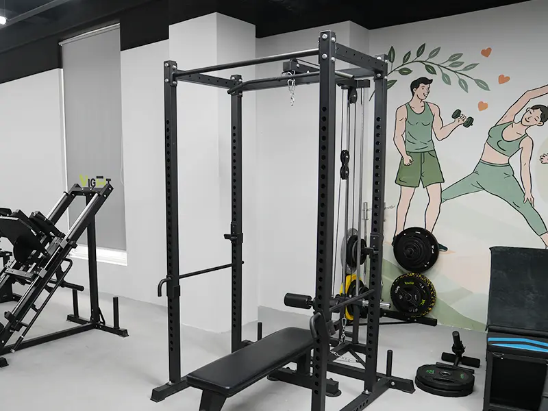 Black power rack with a lat pulldown, low row attachment and weight bench in a showroom.