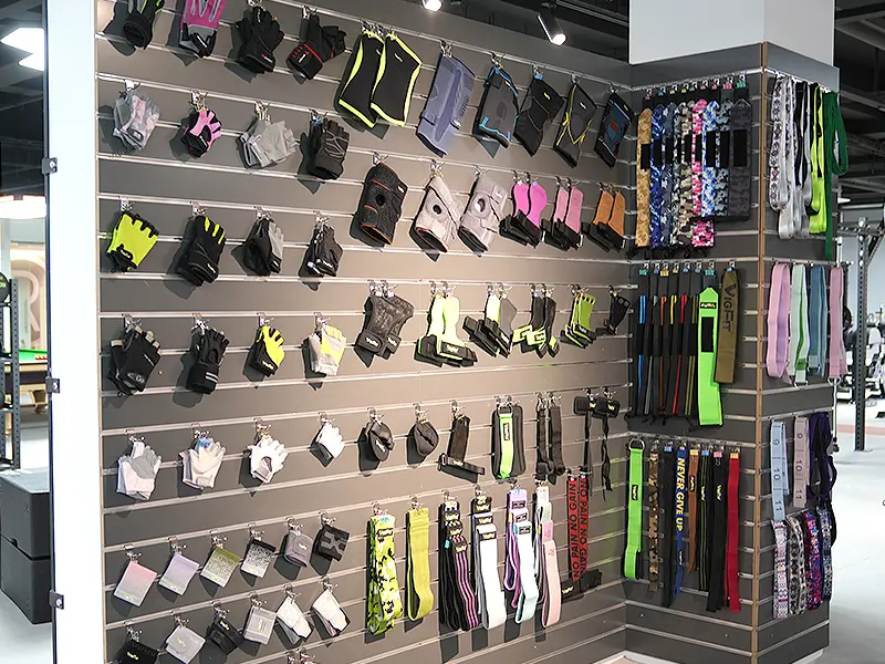 Training gloves, lifting grips, wrist wraps, straps and support accessories displayed in a fitness showroom.