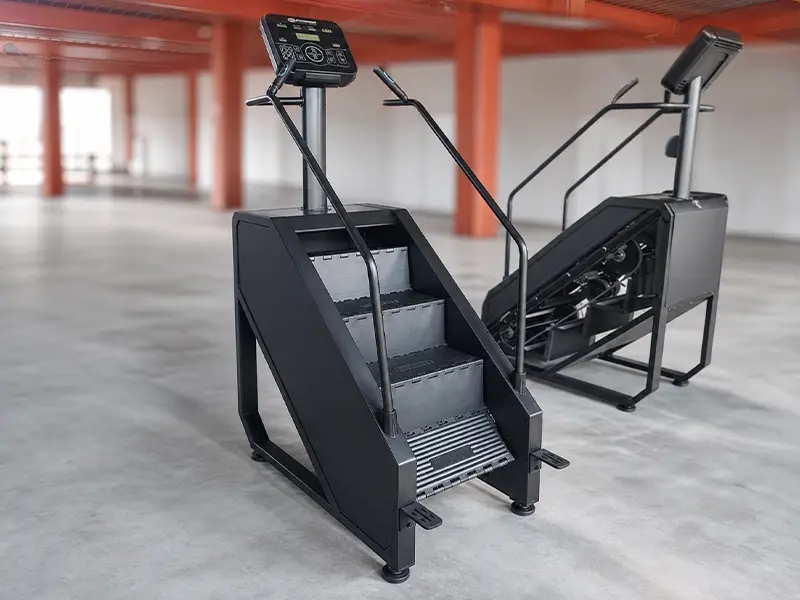 Two black stair climbers with rotating steps, handrails and display consoles
