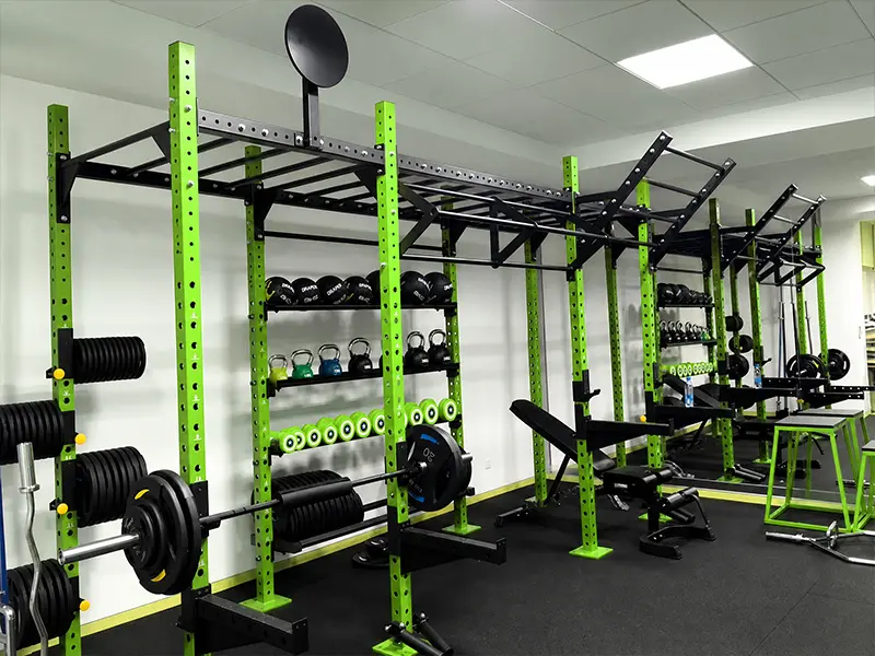 Green and black functional training rig with monkey bars, squat stations and integrated equipment storage