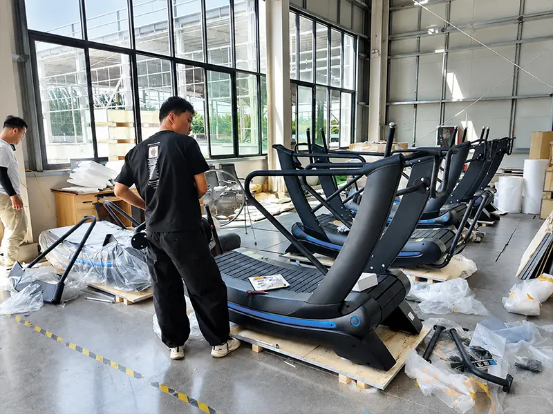Technicians assembling curved treadmills during bulk order production