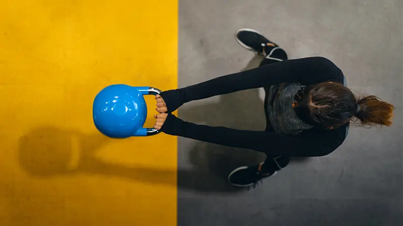 Woman performing goblet squats as part of her full body dumbbell workout at home